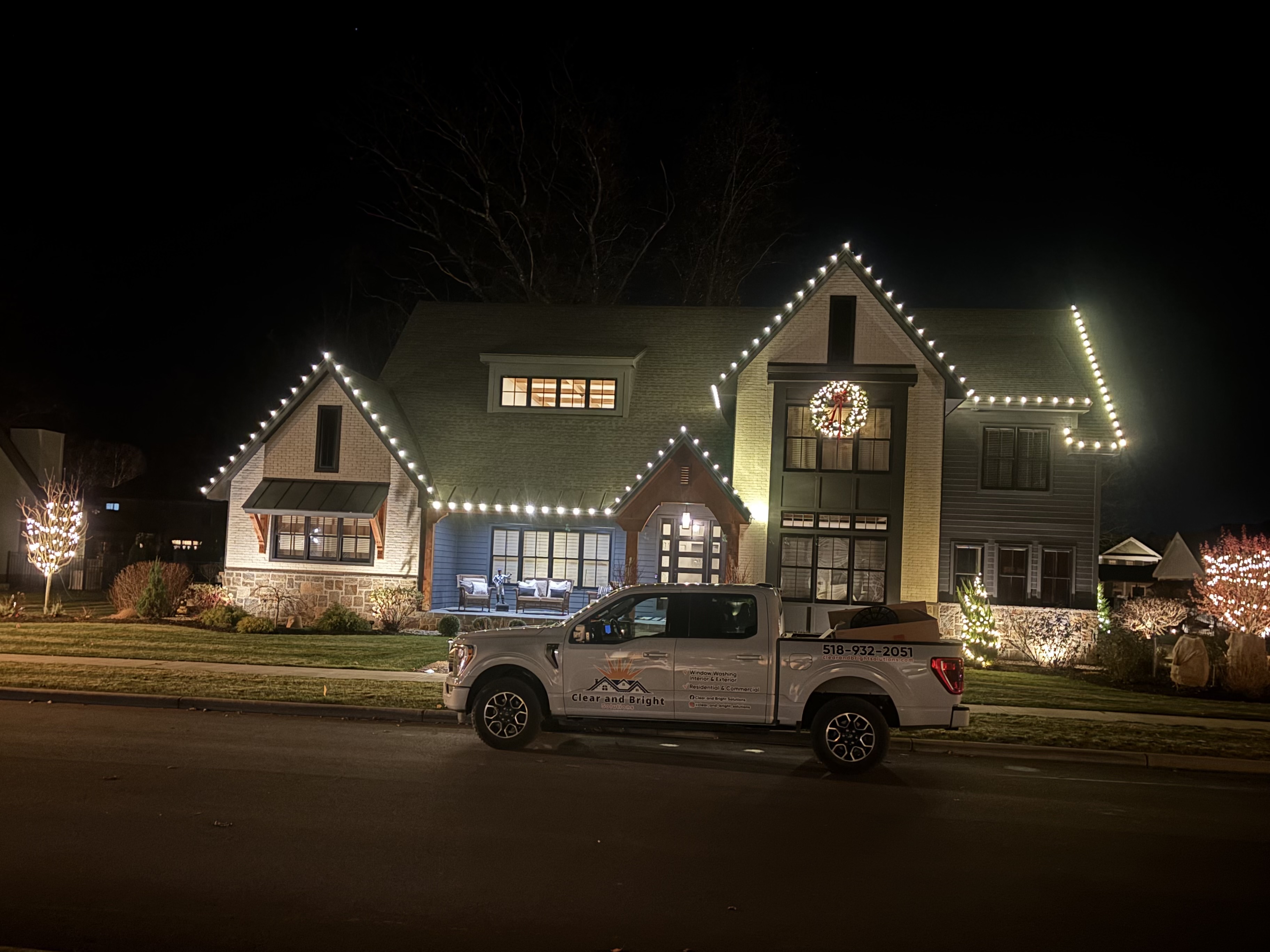 Clear and Bright Solutions truck in front of a holiday lit home